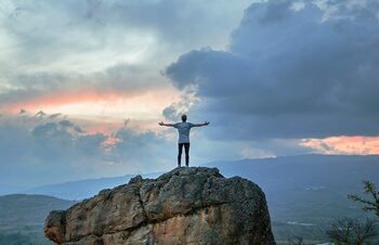 joshua earle 9idqIGrLuTE unsplash Outstreached hands person top of rock 400